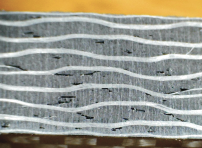 Photo 1-Abrasive waterjet machined, 3/16” thick commercial carbon fiber under 30X magnification.
